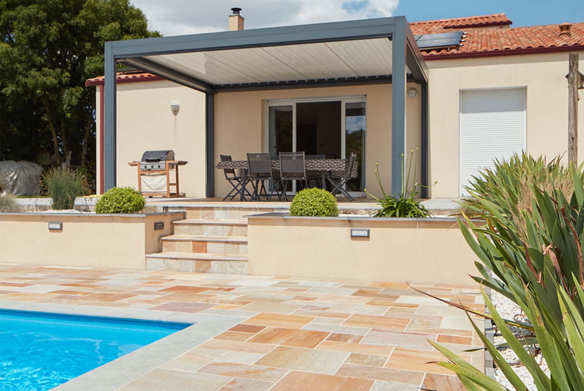 Une maison moderne avec piscine se dresse majestueusement, ses lignes épurées mettant en valeur la terrasse en albino jaune. La terrasse, baignée de lumière, offre un espace de détente luxueux, en parfaite harmonie avec le bleu scintillant de la piscine.