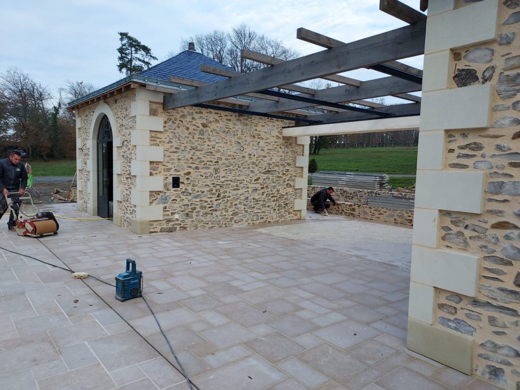 Image d’une rénovation en cours à Cholet : le sol est réalisé en calcaire Alhambra, posé en opus 4, pour conserver la cohérence architecturale avec les murs en pierre existants.