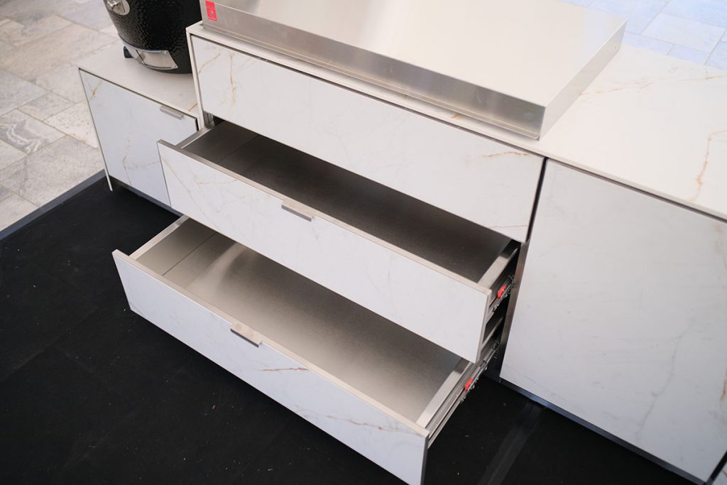 Module de rangement de cuisine extérieure en Ceratop® finition marbre clair, tiroirs coulissants en inox ouverts