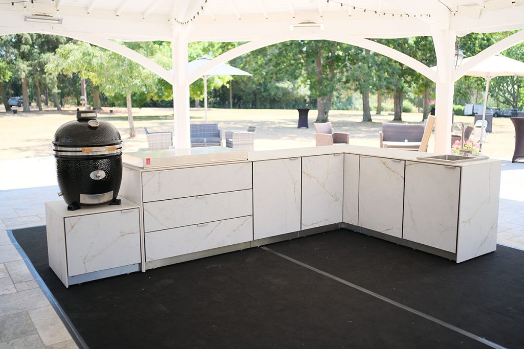Cuisine extérieure modulaire en Ceratop® finition marbre clair en configuration angle, avec tiroirs, évier intégré et espace pour barbecue kamado